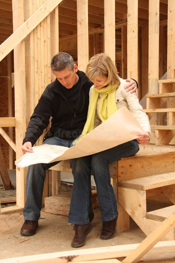 Happy couple going over the blue prints of their new home still under construction. Happy couple going over the blue prints of their new home still under construction.