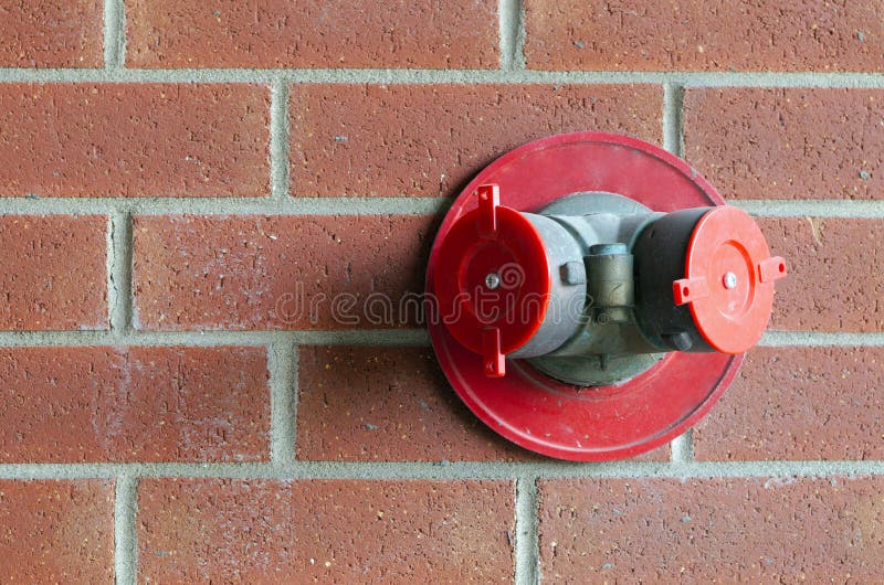 Fire extinguisher sprinkler connection on red brick wall