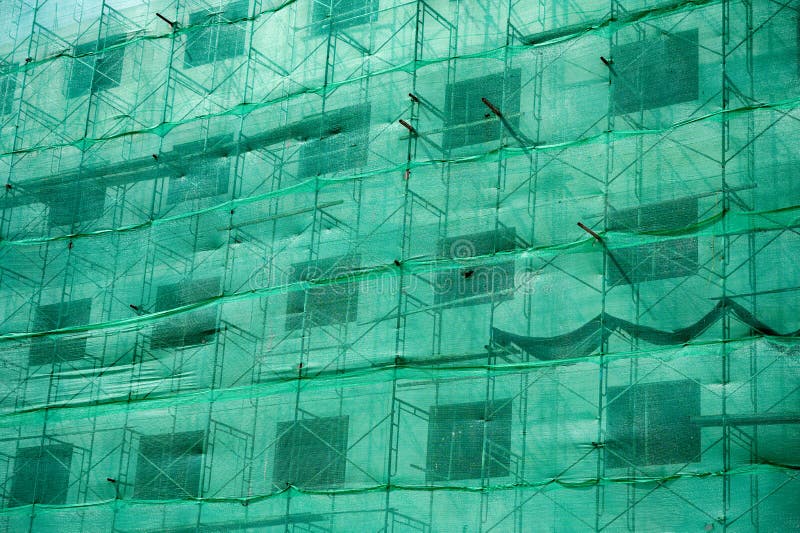 Building structure with green netting shade and scaffolding