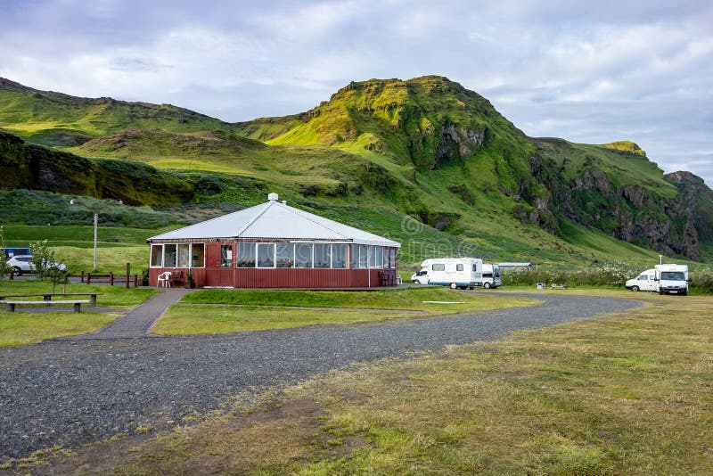 Budova z turista kemp táborníci zelený kopce výše obec v jižní island během krásný západ slunce.
