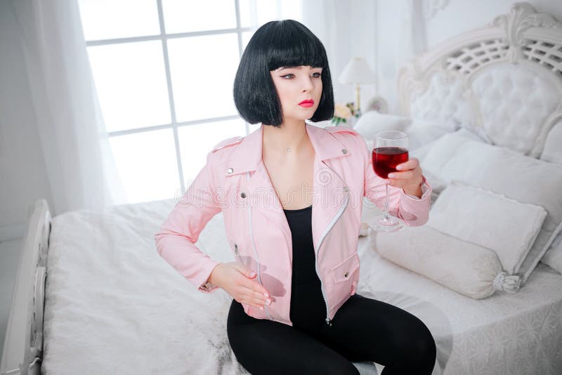 Buitenissige manier Houden het glamour synthetische meisje, de valse pop met lege blik en het korte zwarte haar een glas rode wij stock foto Buitenissige manier Houden het glamour synthetische meisje, de valse pop met lege blik en het korte zwarte haar een glas rode wij stock foto