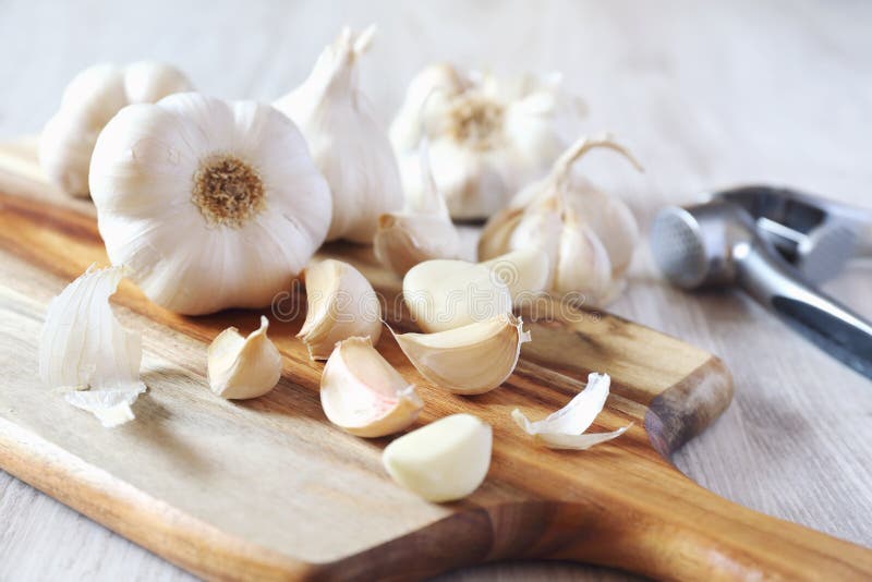 Bulbos Del Ajo En La Prensa De La Tabla De Cortar Y De Ajo Foto de