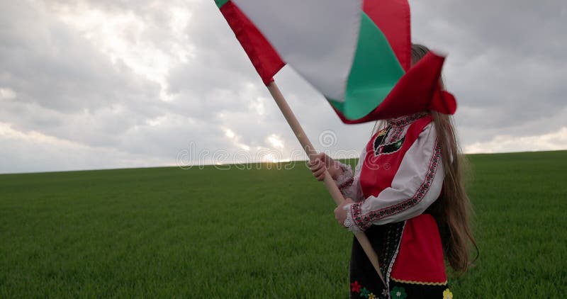 Bulgaars meisje in folklore kostuum zwaait trots bulgaarse vlag op de dag van de bevrijding van bulgarije op 3 maart