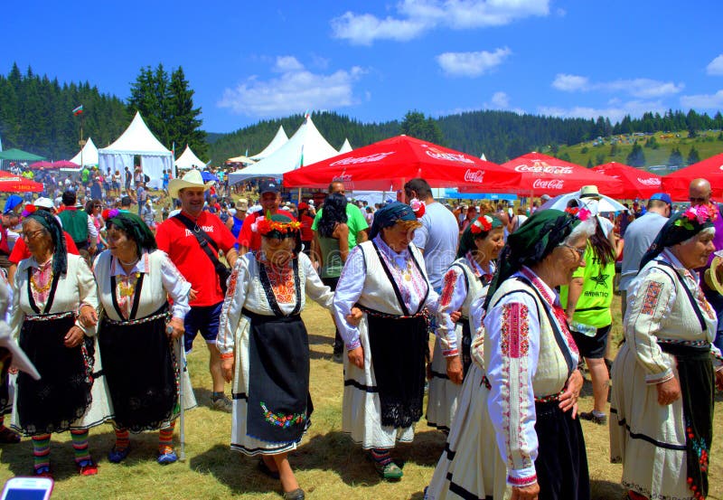 Elderly women folklore singers group dressed in traditional authentic costumes at Folklore Festival Rozhen in beautiful scenery of Rhodope Mountains.Every 4th year in July, Bulgarians of all over the country gather below the peak of Rozhen for a festival, where singers and instrumentalists sing and play on a several scenes. Elderly women folklore singers group dressed in traditional authentic costumes at Folklore Festival Rozhen in beautiful scenery of Rhodope Mountains.Every 4th year in July, Bulgarians of all over the country gather below the peak of Rozhen for a festival, where singers and instrumentalists sing and play on a several scenes.