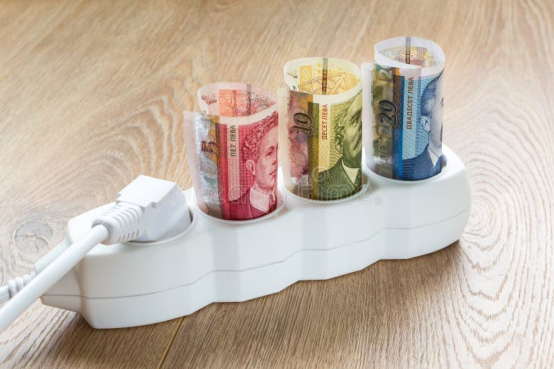 Bulgarian leva banknotes and white power plug inserted into an extension socket on a wooden surface. Cost of electricity and royalty free stock photography