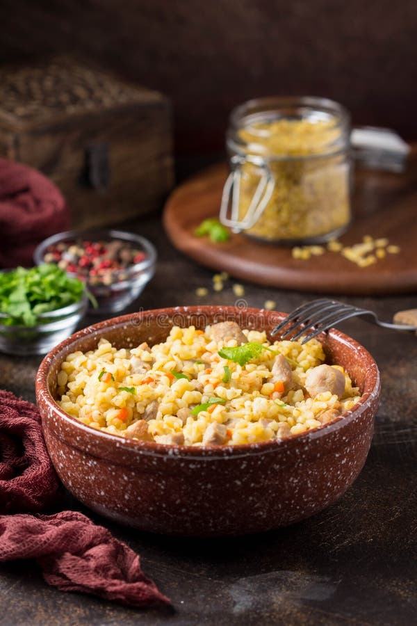 Bulgur with turkey, pork or beef. Eastern dish of rice, tasty traditional food. Stewed meat with grits. Pilaf on dark background stock image Bulgur with turkey, pork or beef. Eastern dish of rice, tasty traditional food. Stewed meat with grits. Pilaf on dark background stock image