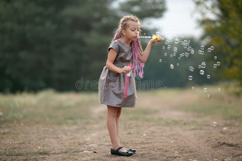 Bulles de savon de soufflement de fille heureuse d'enfant sur la promenade en parc photo libre de droits Bulles de savon de soufflement de fille heureuse d'enfant sur la promenade en parc photo libre de droits