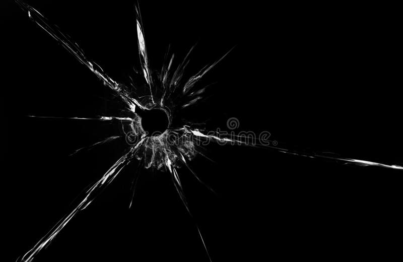 Bullet hole in glass close up on black background