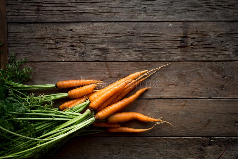 A bunch of carrots . Fresh carrots, beetroot heap with green stems. Raw Carrots and beetroot on rustic wooden back stock photo A bunch of carrots . Fresh carrots, beetroot heap with green stems. Raw Carrots and beetroot on rustic wooden back stock photo
