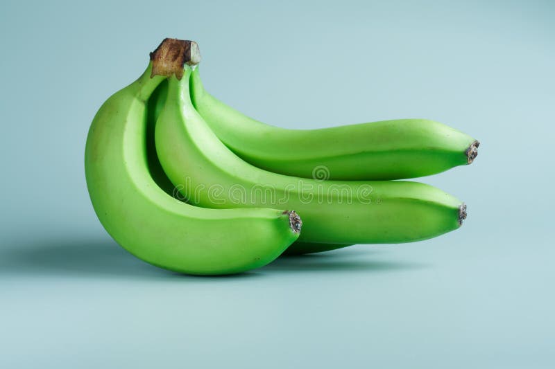 A bunch of fresh green bananas on a pastel blue-green background. Copy space. Daylight stock photos A bunch of fresh green bananas on a pastel blue-green background. Copy space. Daylight stock photos