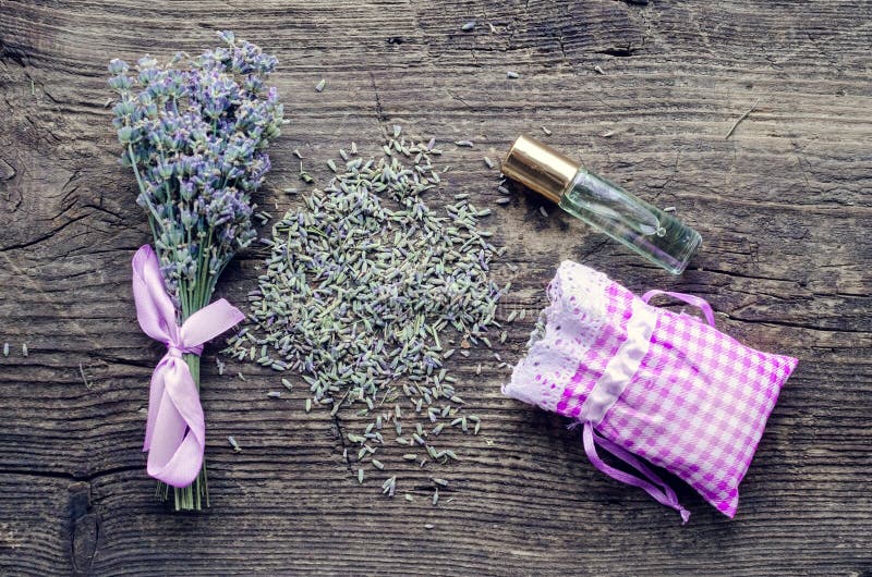 Bunch of lavender flowers, lavender oil and sachet filled with dried lavender on a wooden background. Top view. Bunch of lavender flowers, lavender oil and sachet filled with dried lavender on a wooden background. Top view