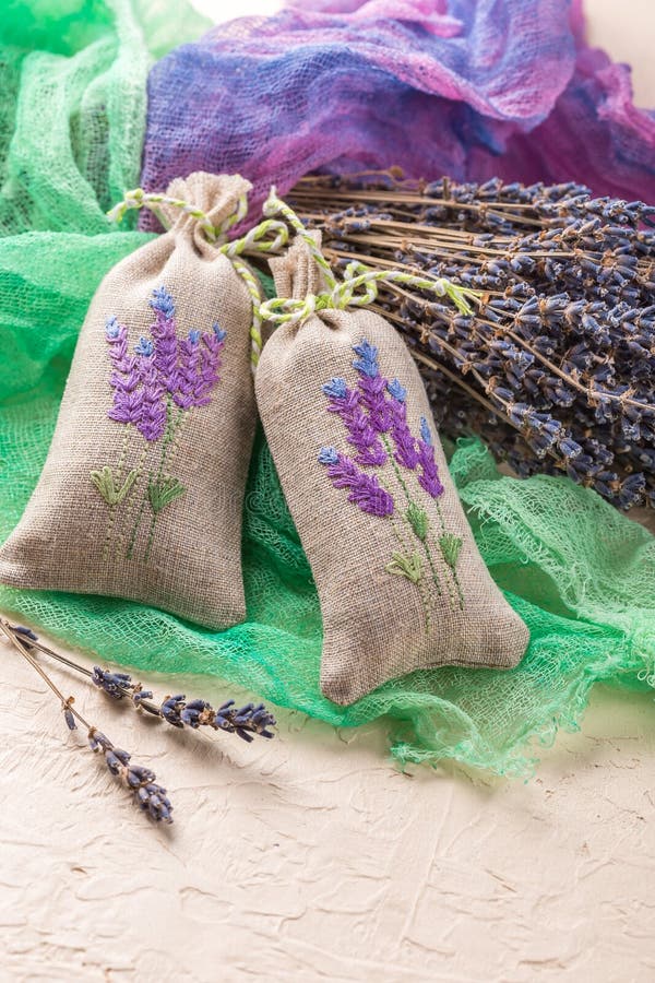 Two aromatic embroidered sachets filled with dried lavender and a bouquet of dry lavender. Two aromatic embroidered sachets filled with dried lavender and a bouquet of dry lavender