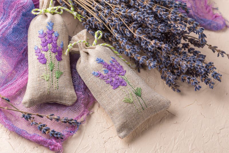 Two aromatic embroidered sachets filled with dried lavender and a bouquet of dry lavender. Two aromatic embroidered sachets filled with dried lavender and a bouquet of dry lavender