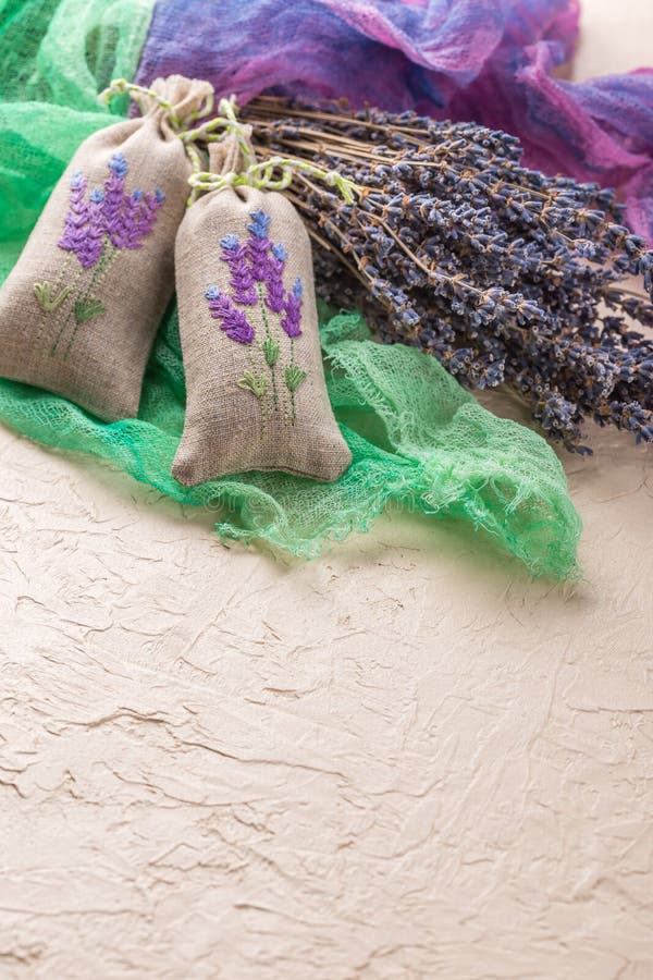 Two aromatic embroidered sachets filled with dried lavender and a bouquet of dry lavender. Two aromatic embroidered sachets filled with dried lavender and a bouquet of dry lavender