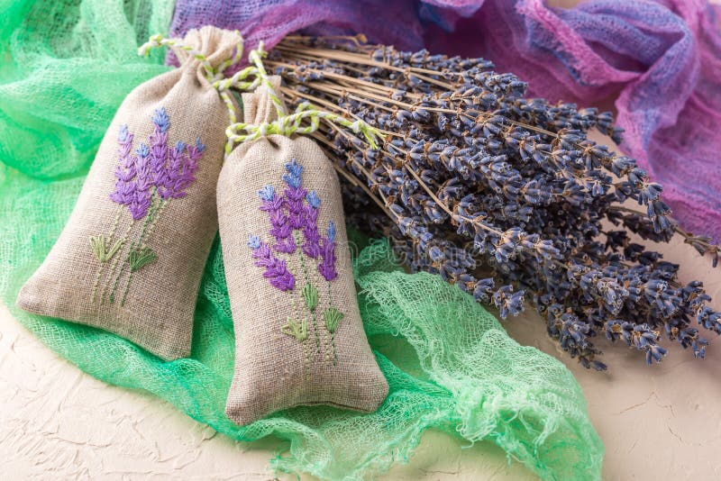 Two aromatic embroidered sachets filled with dried lavender and a bouquet of dry lavender. Two aromatic embroidered sachets filled with dried lavender and a bouquet of dry lavender