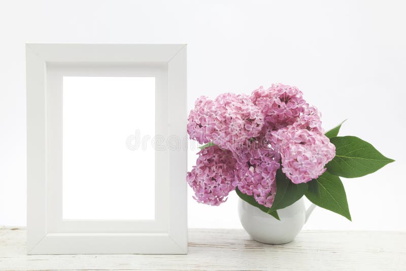 Bunch lilac in vase on wooden table and white frame mock up