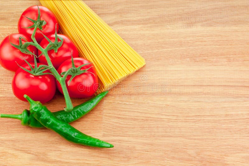 Bunch of spaghetti pasta, green hot peppers and Ripe tomatoes