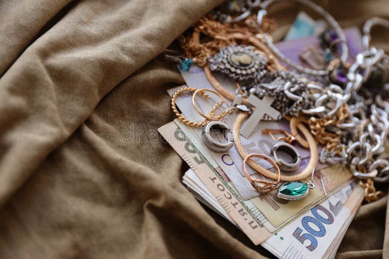Bunch of stolen jewelry and money on military uniform cloth fabric. Looting by Russian soldiers in the Ukrainian cities during the