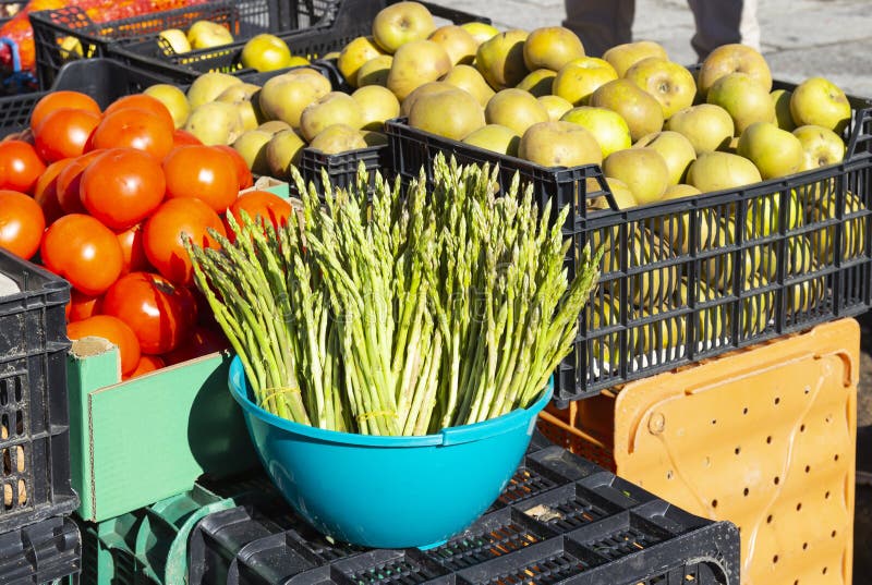 Bunch of wild green asparagus with a background of locally grown tomatoes at street markets