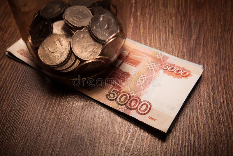 Bundle of bank notes and a glass jar with coins