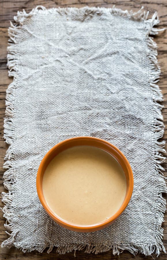 Bowl of tahini sauce on the wooden background. Bowl of tahini sauce on the wooden background