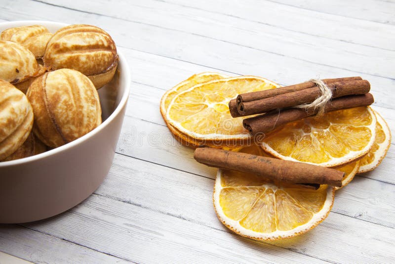 Bunke med tokiga kakor - och orange skivor med kanel på en ljus träbakgrund arkivbild Bunke med tokiga kakor - och orange skivor med kanel på en ljus träbakgrund arkivbild