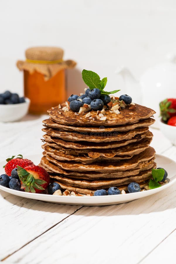 Bunt av hemlagade läckra pannkakor för frukost på den vita tabellen som är vertikala arkivfoton Bunt av hemlagade läckra pannkakor för frukost på den vita tabellen som är vertikala arkivfoton