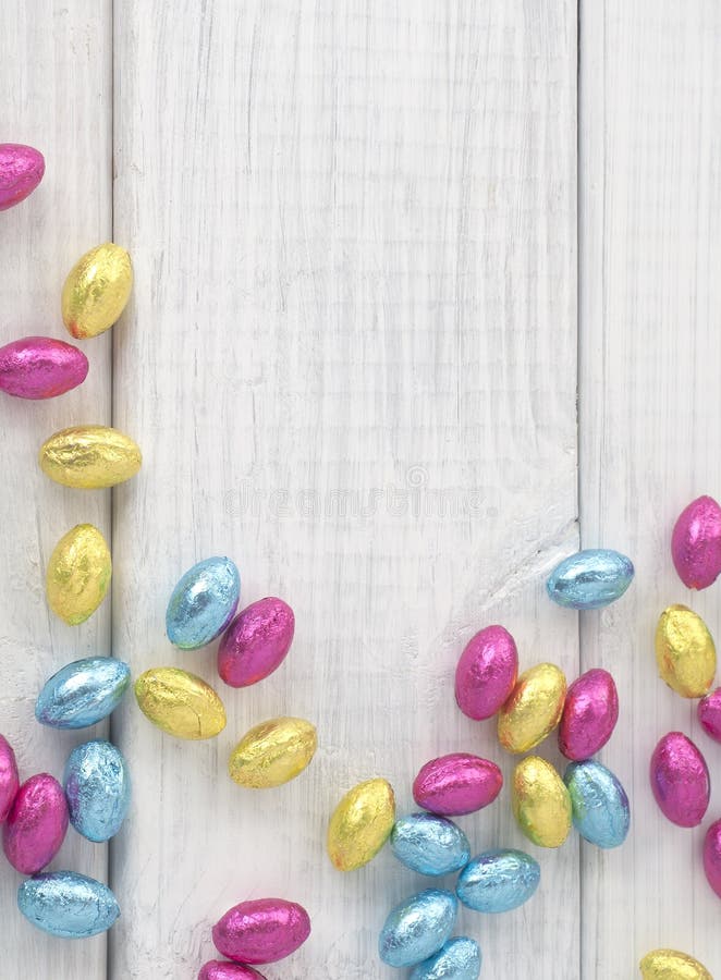 Bunte eingewickelte Schokoladen-Ostereier zerstreuten auf weißes Brett-Hintergrund mit Raum oder Raum für Text, Kopie oder Wörter. lizenzfreies stockbild Bunte eingewickelte Schokoladen-Ostereier zerstreuten auf weißes Brett-Hintergrund mit Raum oder Raum für Text, Kopie oder Wörter. lizenzfreies stockbild
