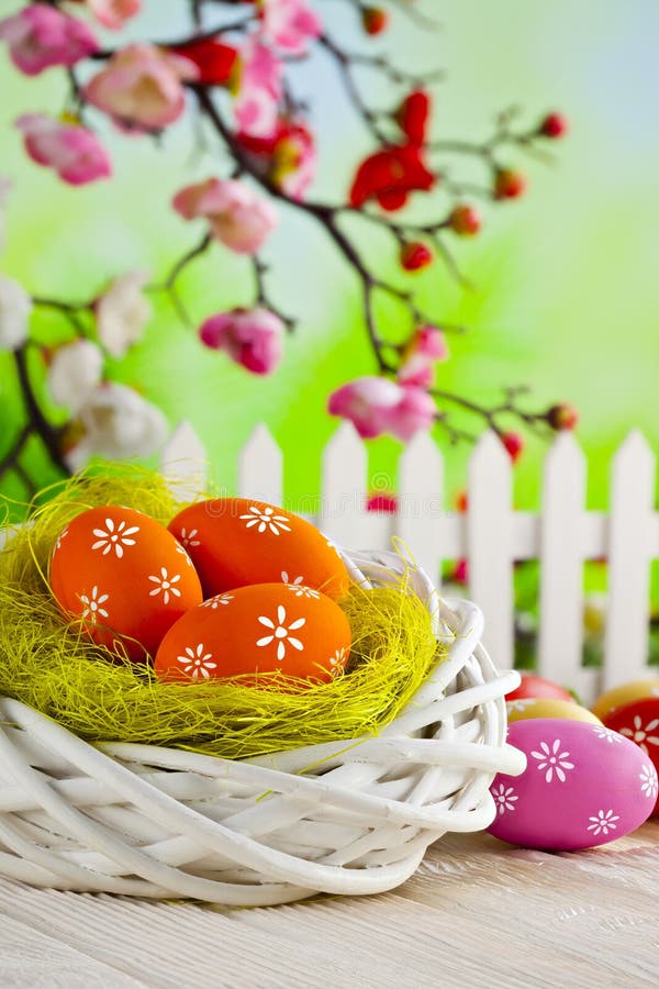 Bunte Ostereier, weißes Nest und Zaun auf Holztisch stockbilder