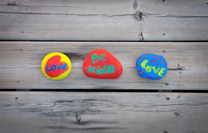 Colorful rocks with love and be kind words in a wood background. Colorful rocks with love and be kind words in a wood background