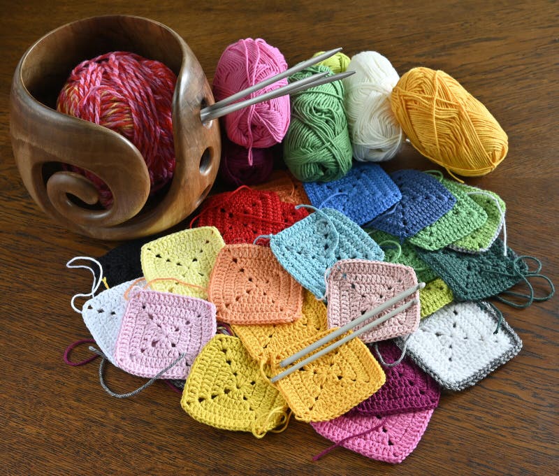 Bunte Strickspinnen aus Wolle und einer hölzernen Garnschüssel stockfoto
