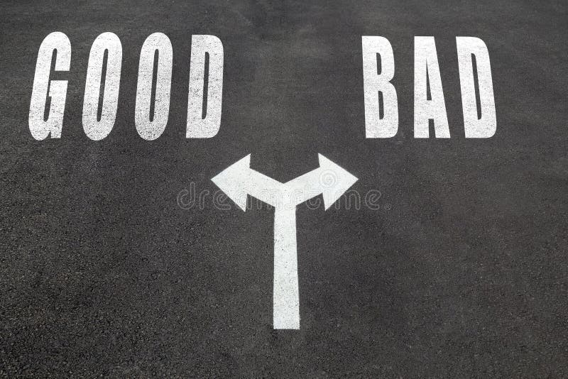 Good vs bad choice concept, two direction arrows on asphalt. Good vs bad choice concept, two direction arrows on asphalt.
