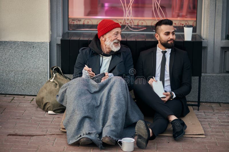 Buon mendicante incontra un uomo d'affari per strada fotografia stock Buon mendicante incontra un uomo d'affari per strada fotografia stock