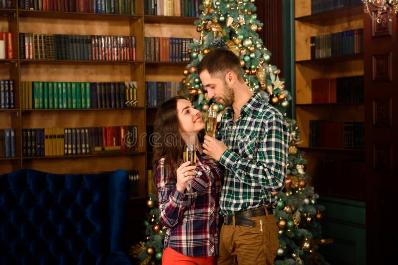 Buon Natale e buon anno La coppia attraente sta celebrando la festa a casa insieme, bevendo il champagne e fotografia stock libera da diritti Buon Natale e buon anno La coppia attraente sta celebrando la festa a casa insieme, bevendo il champagne e fotografia stock libera da diritti