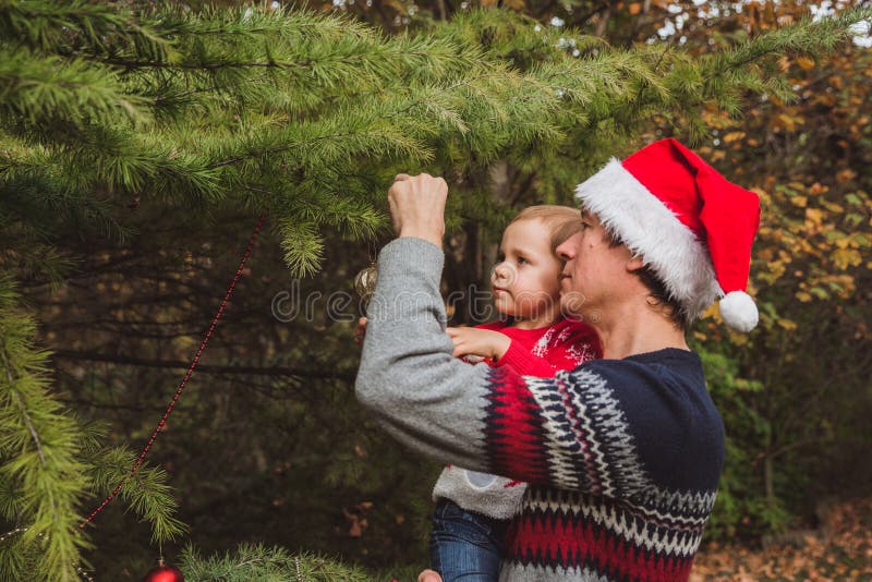 Buon Natale e feste felici Padre nel Natale rosso cappello e figlia in maglione rosso che decorano il Natale immagini stock libere da diritti Buon Natale e feste felici Padre nel Natale rosso cappello e figlia in maglione rosso che decorano il Natale immagini stock libere da diritti
