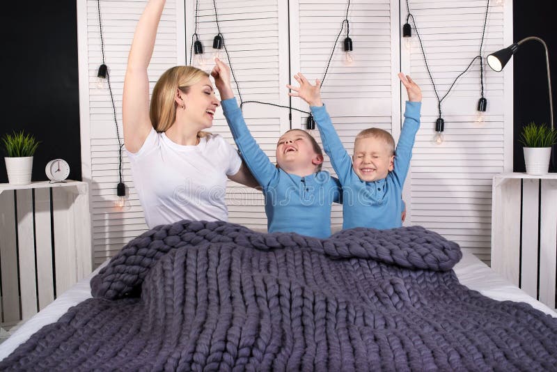 Buongiorno! La madre ed i due giovani figli stanno allungando a letto Risveglio positivo immagine stock Buongiorno! La madre ed i due giovani figli stanno allungando a letto Risveglio positivo immagine stock