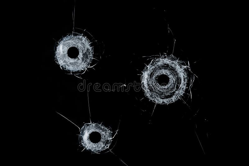 Buracos de bala triplos de vidro quebrados no vidro isolado no preto