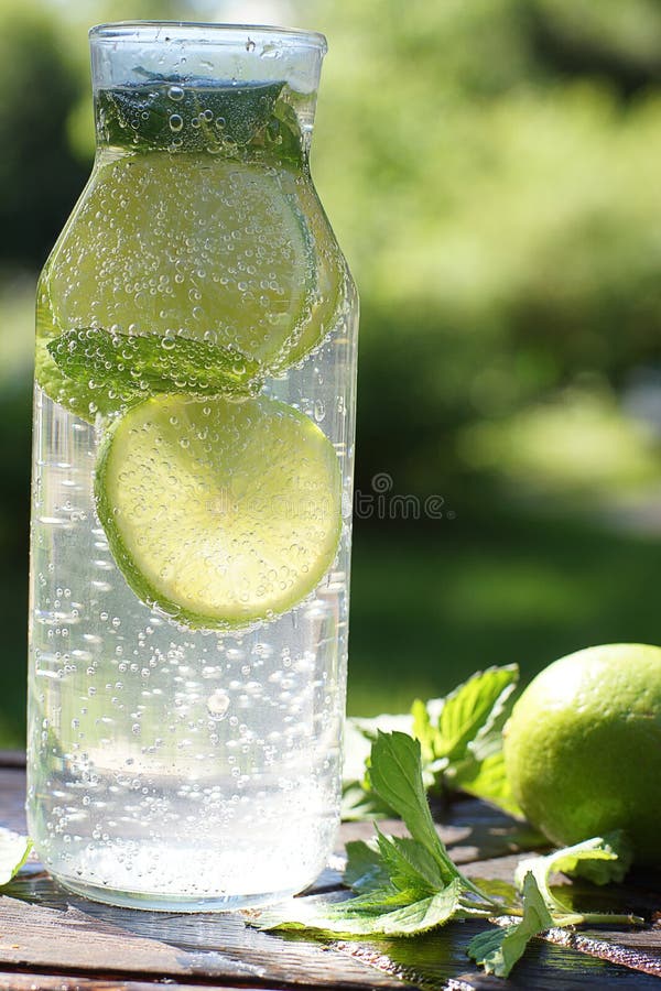 Burbujas hermosas en un cóctel hecho en casa del mojito en una botella transparente con la menta y la cal