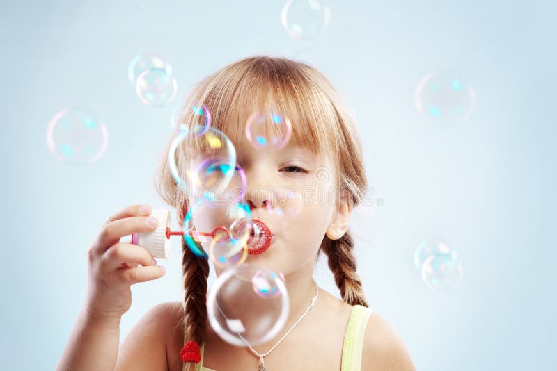 Burbujas que soplan de la niña