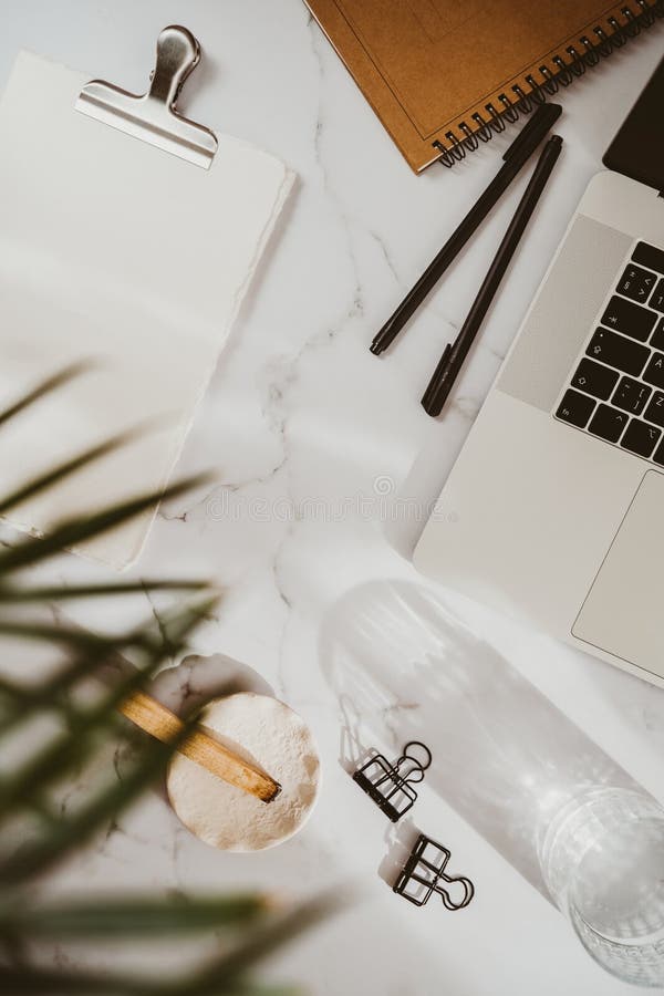 White desk office with laptop, stationery, palo santo stick and green plant flat lay. Top view. Copy space. Modern aesthetic workspace concept. White desk office with laptop, stationery, palo santo stick and green plant flat lay. Top view. Copy space. Modern aesthetic workspace concept