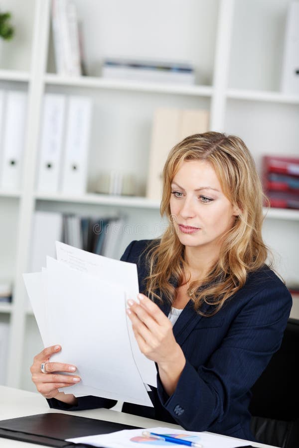 Femme d'affaires lisant des documents à son bureau photographie stock