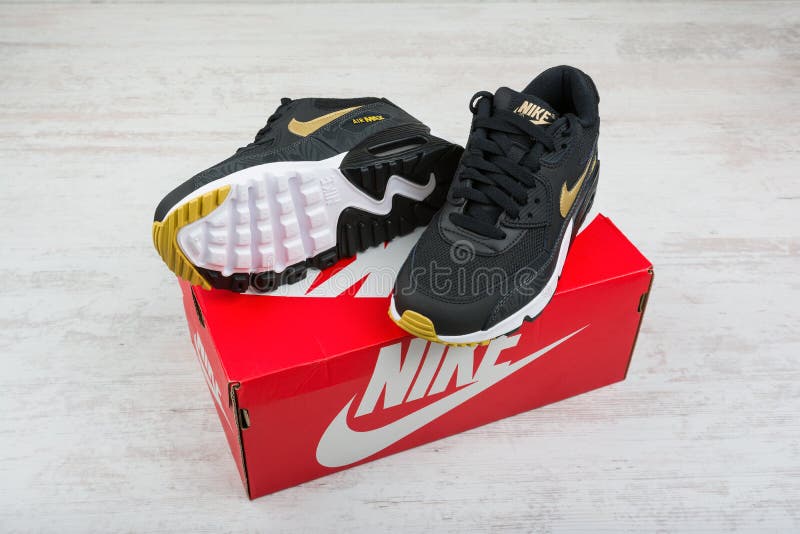 BURGAS, BULGARIA - DECEMBER 30, 2016: Nike Air MAX women`s shoes - sneakers in black, on white wooden background. Nike is a global sports clothes and running shoes retailer