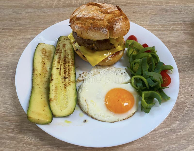 Burger with cheese and fried egg, fried zucchini, cherry tomatoes and cut leek stock photos Burger with cheese and fried egg, fried zucchini, cherry tomatoes and cut leek stock photos