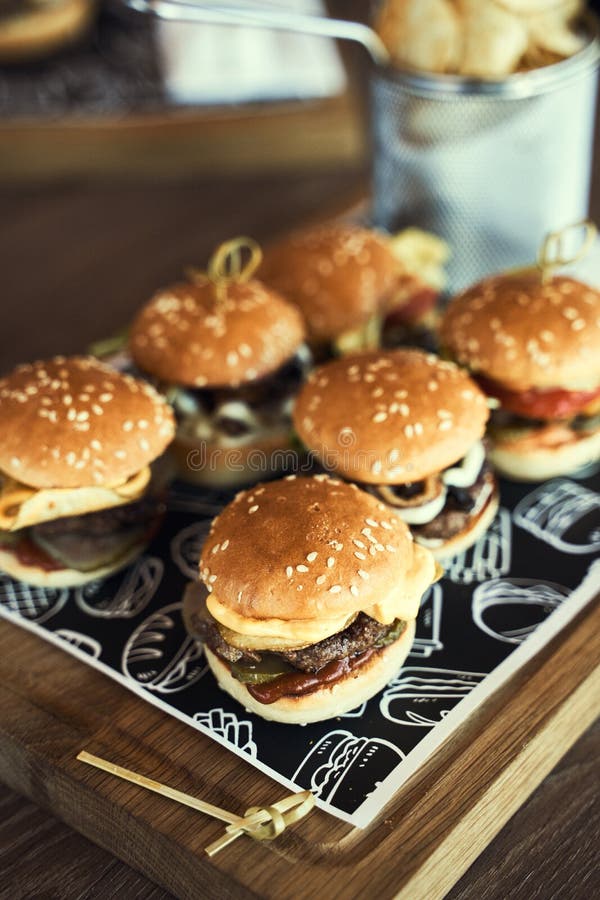 Burger e patatine fritte su tavole di legno isolate su fondo nero immagini stock Burger e patatine fritte su tavole di legno isolate su fondo nero immagini stock