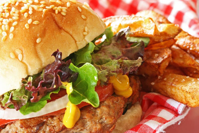 Vicino alla griglia, hamburger di tacchino, lattuga, pomodoro, cipolla, senape, oro e salate patatine fritte sul lato.