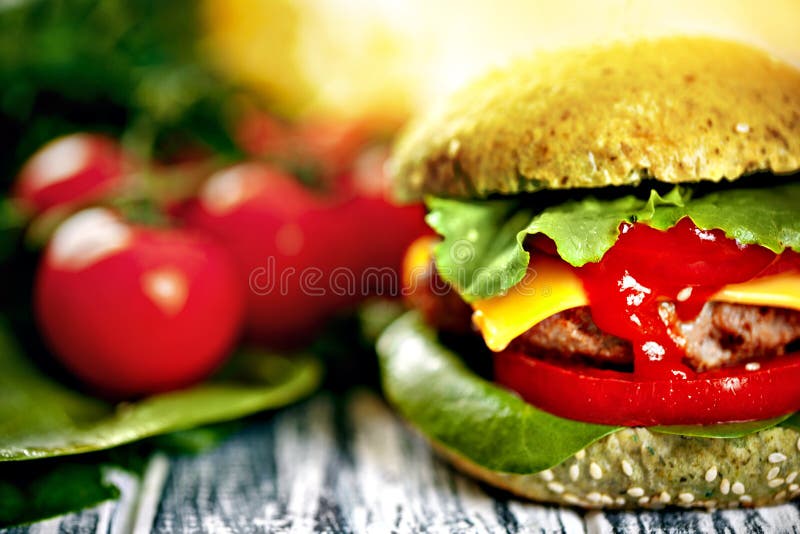 Burger με το πράσινο κουλούρι και τα φρέσκα λαχανικά στοκ φωτογραφία με δικαίωμα ελεύθερης χρήσης Burger με το πράσινο κουλούρι και τα φρέσκα λαχανικά στοκ φωτογραφία με δικαίωμα ελεύθερης χρήσης