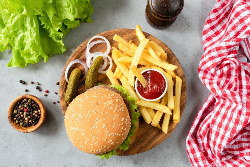Burger με το σουσάμι, τα τηγανητά, τα τουρσιά και τη σαλάτα μαρουλιού στοκ φωτογραφία