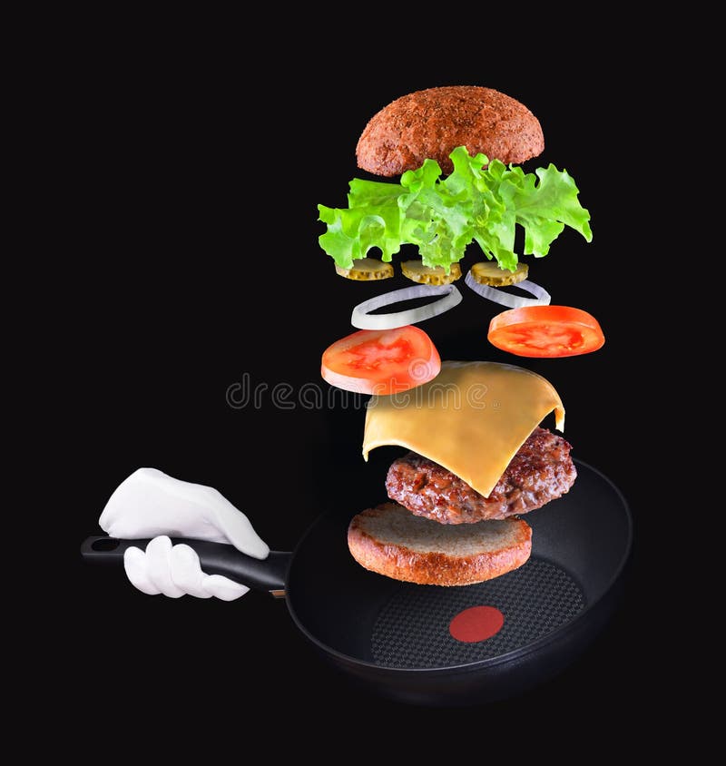 Burgerteilfliegen in einer Luft auf Schwarzem Hand, die Bratpfanne h?lt stockfotografie Burgerteilfliegen in einer Luft auf Schwarzem Hand, die Bratpfanne h?lt stockfotografie