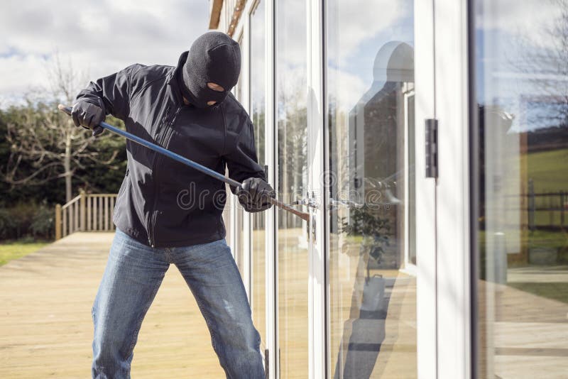 Burglar breaking into a house via a window with a crowbar. Burglar or thief breaking into a home through window with a crowbar stock photo Burglar breaking into a house via a window with a crowbar. Burglar or thief breaking into a home through window with a crowbar stock photo