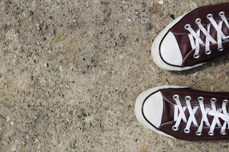Burgundy sneakers na szorstkim bruku z udzia?ami pok?j dla kopii obrazy royalty free Burgundy sneakers na szorstkim bruku z udzia?ami pok?j dla kopii obrazy royalty free